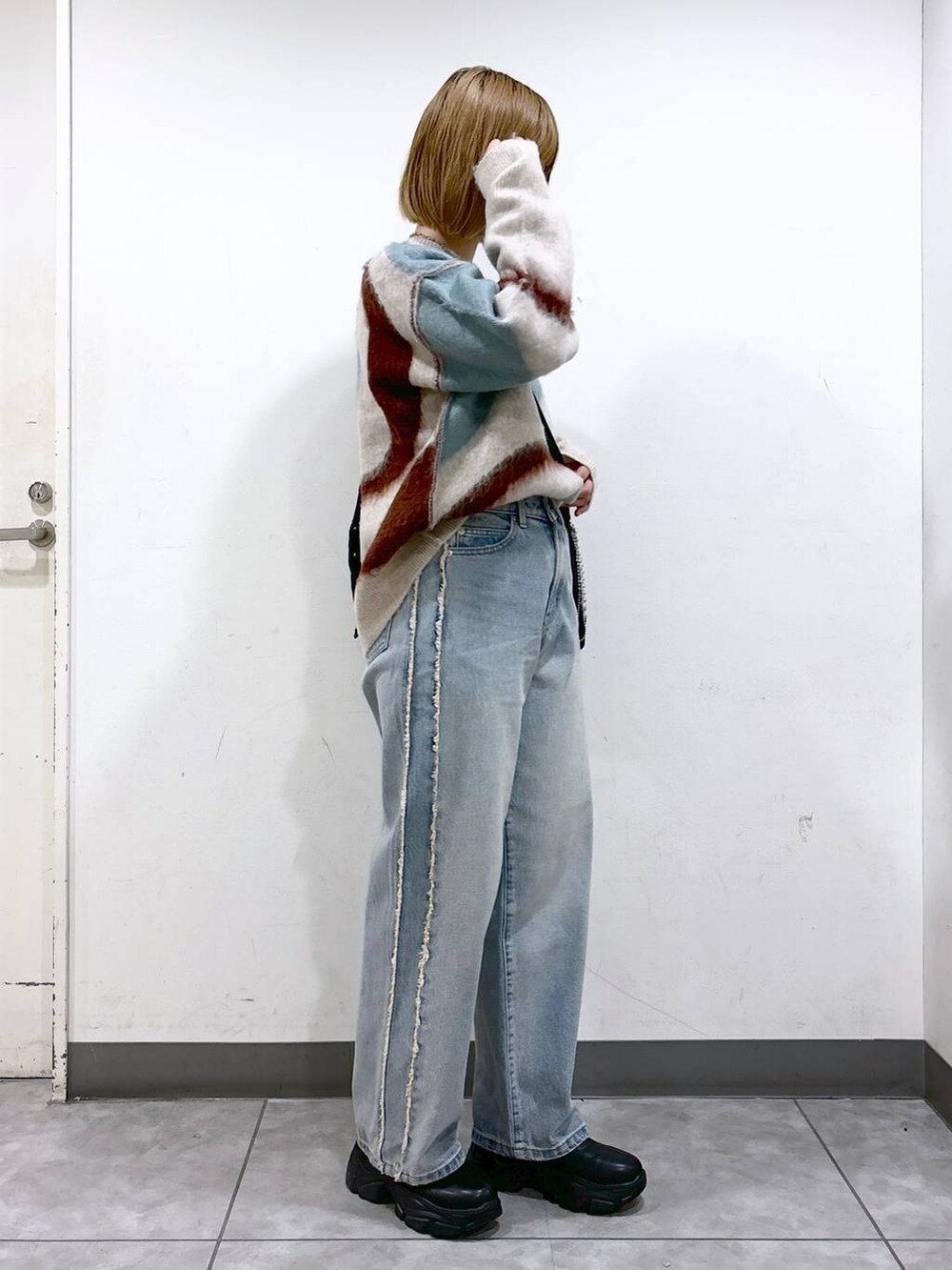 ブルー系のデニムパンツ、ブラック系のブーツ、ブラック系のショルダーバッグを着用したレディースの秋コーディネートの2枚目の写真