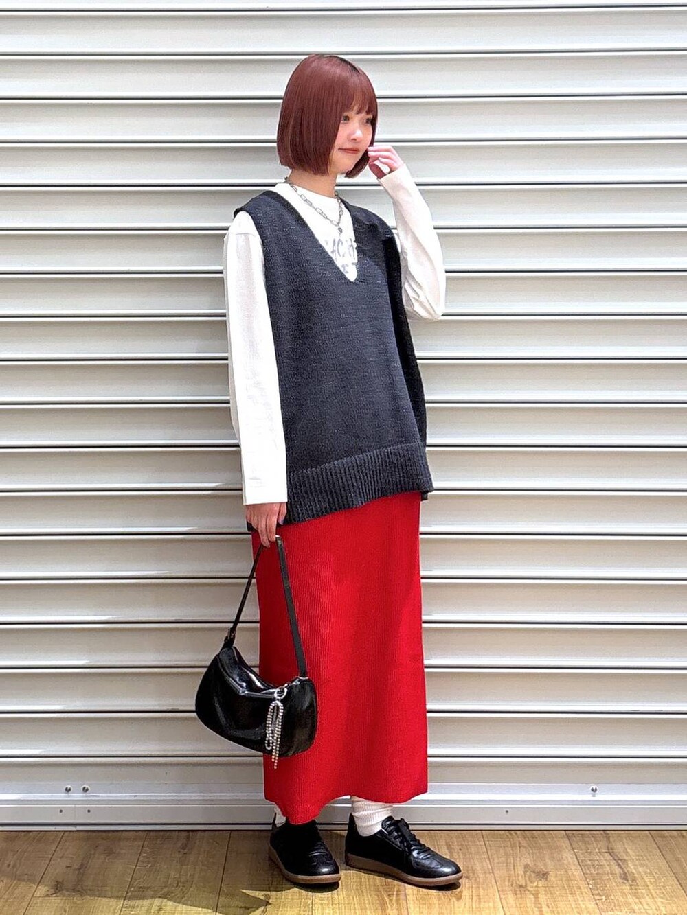 レッド系のスカート、ホワイト系のTシャツ/カットソー、シルバー系のトートバッグを着用したレディースの春コーディネートの2枚目の写真