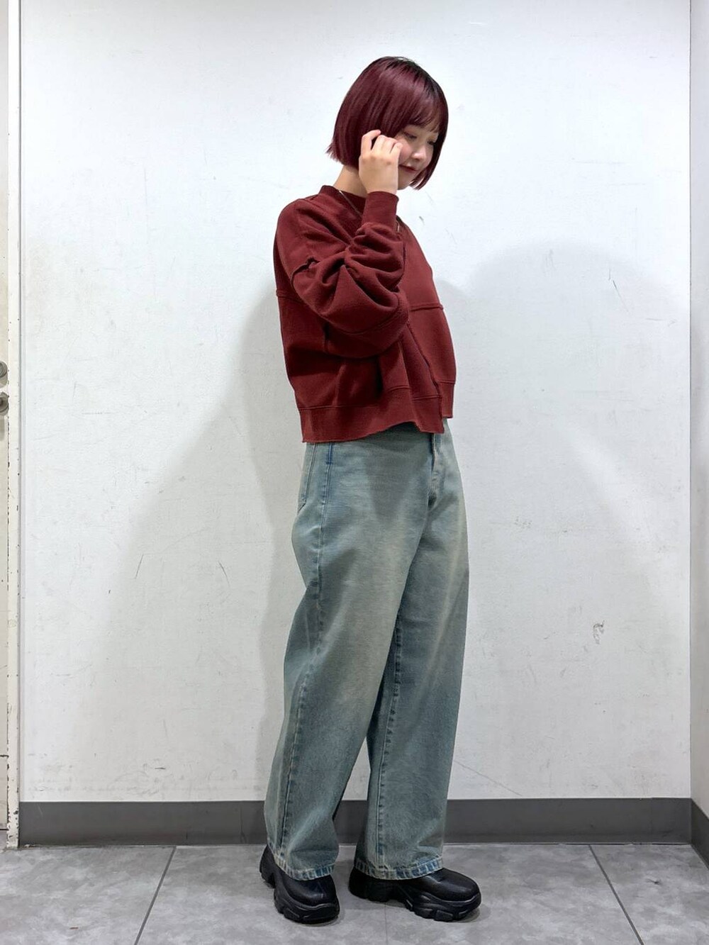 ブルー系のデニムパンツ、ブラック系のブーツ、ブラック系のショルダーバッグを着用したレディースの秋コーディネートの4枚目の写真