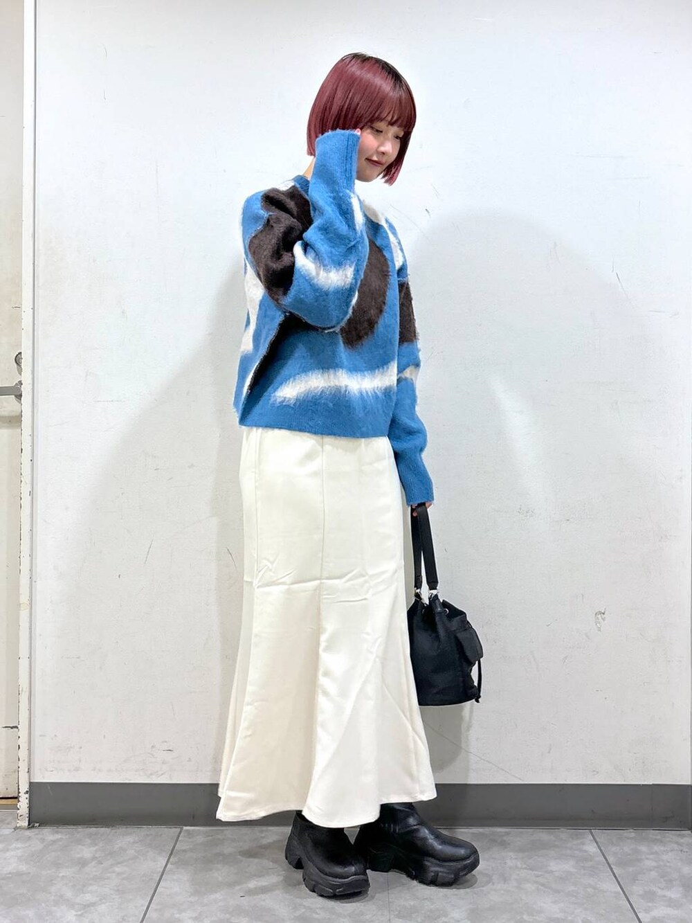 ホワイト系のスカート、ブラック系のショルダーバッグ、ブルー系のニット/セーターを着用したレディースの秋コーディネートの2枚目の写真