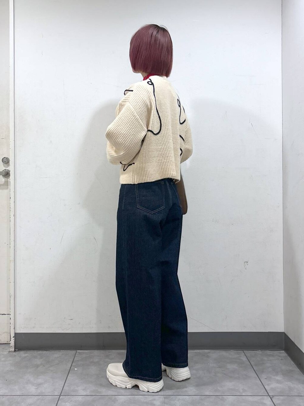 レッド系のニット/セーター、ホワイト系のブーツ、ブラウン系のショルダーバッグを着用したレディースの冬コーディネートの3枚目の写真