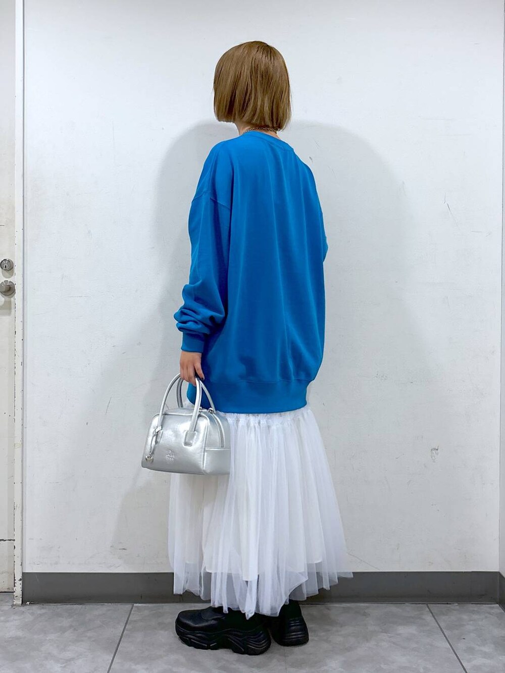 ベージュ系のスカート、ブルー系のスウェット、シルバー系のボストンバッグを着用したレディースの秋コーディネートの3枚目の写真