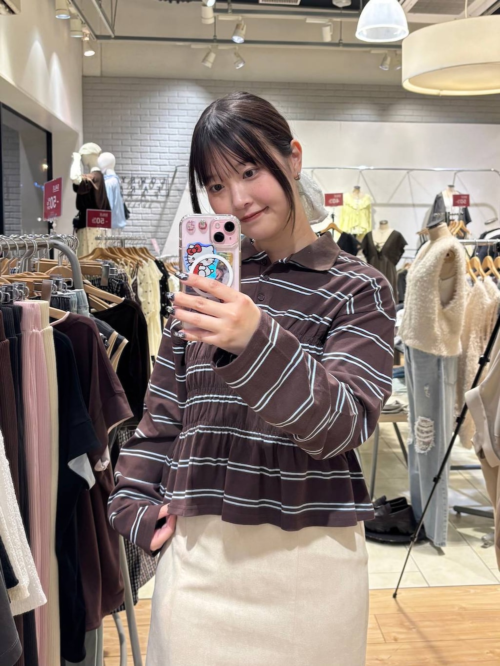 ホワイト系のスカート、ブラウン系のポロシャツを着用したレディースの秋コーディネートの2枚目の写真