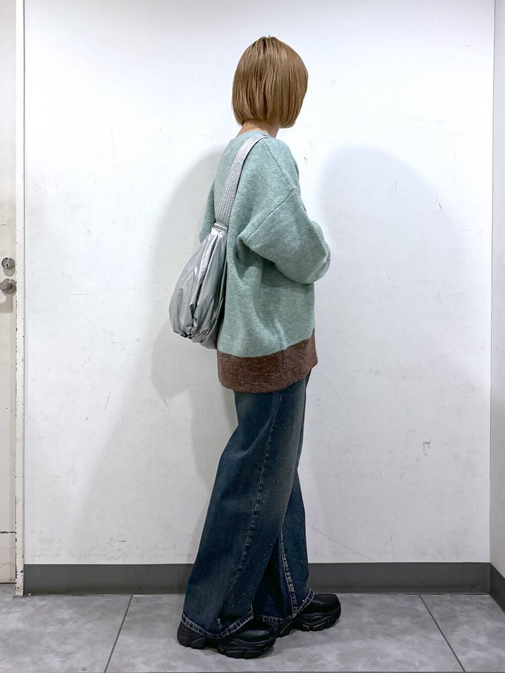 ブルー系のデニムパンツ、ブラック系のブーツ、グリーン系のニット/セーターを着用したレディースの秋コーディネートの3枚目の写真