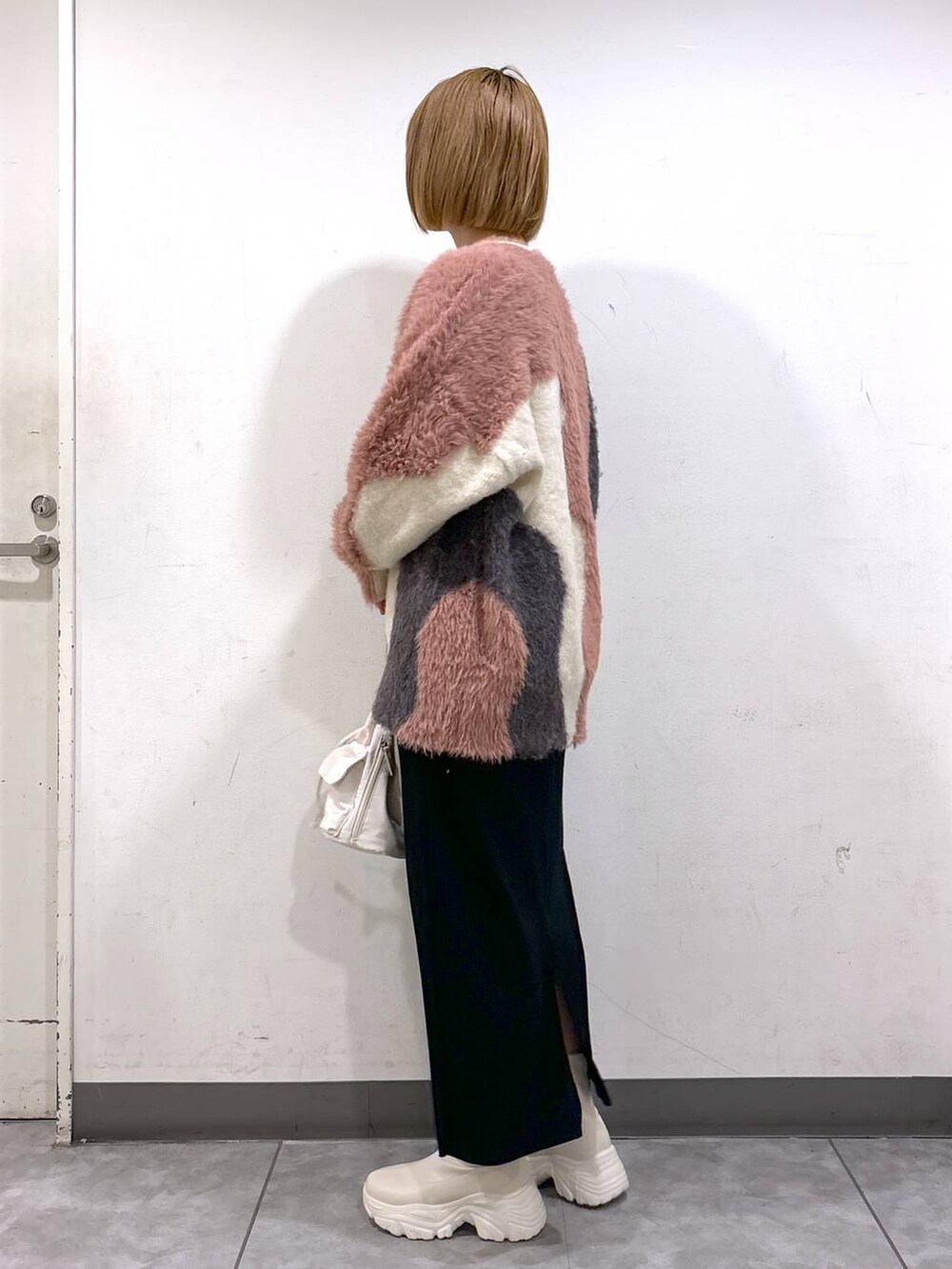 ブラック系のスカート、ホワイト系のブーツ、ホワイト系のショルダーバッグを着用したレディースの秋コーディネートの3枚目の写真