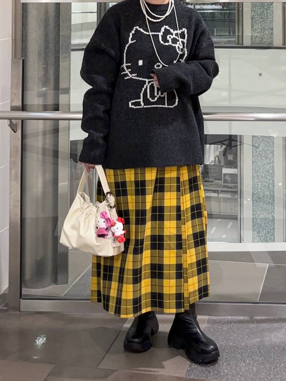 イエロー系のスカート、ホワイト系のショルダーバッグ、グレー系のニット/セーターを着用したレディースの秋コーディネートの3枚目の写真