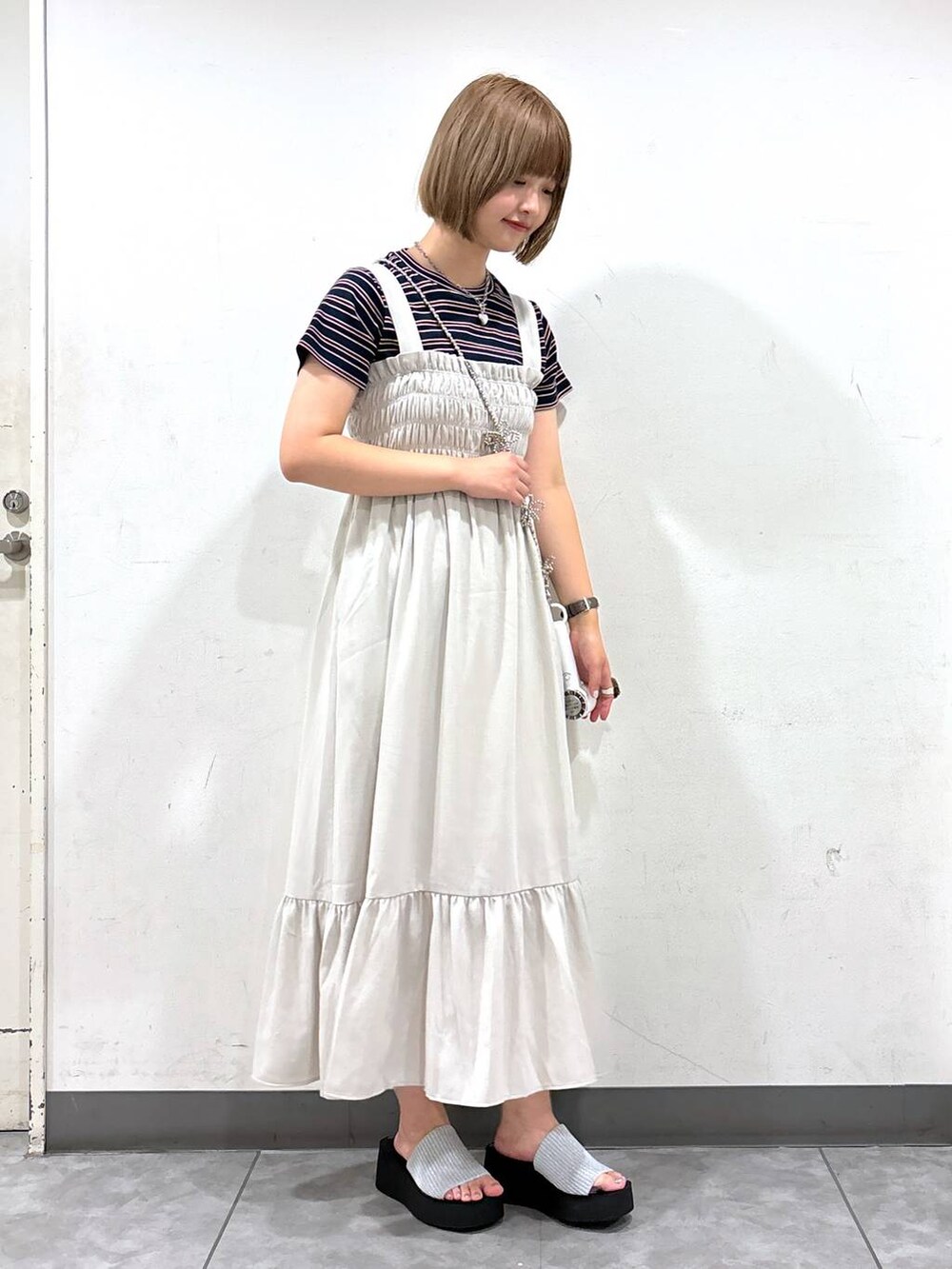 ホワイト系のワンピース、シルバー系のサンダル、ブラウン系のTシャツ/カットソーを着用したレディースの夏コーディネートの2枚目の写真