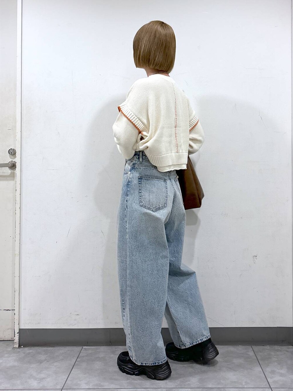 ホワイト系のニット/セーター、ブルー系のデニムパンツ、ブラウン系のショルダーバッグを着用したレディースの秋コーディネートの3枚目の写真