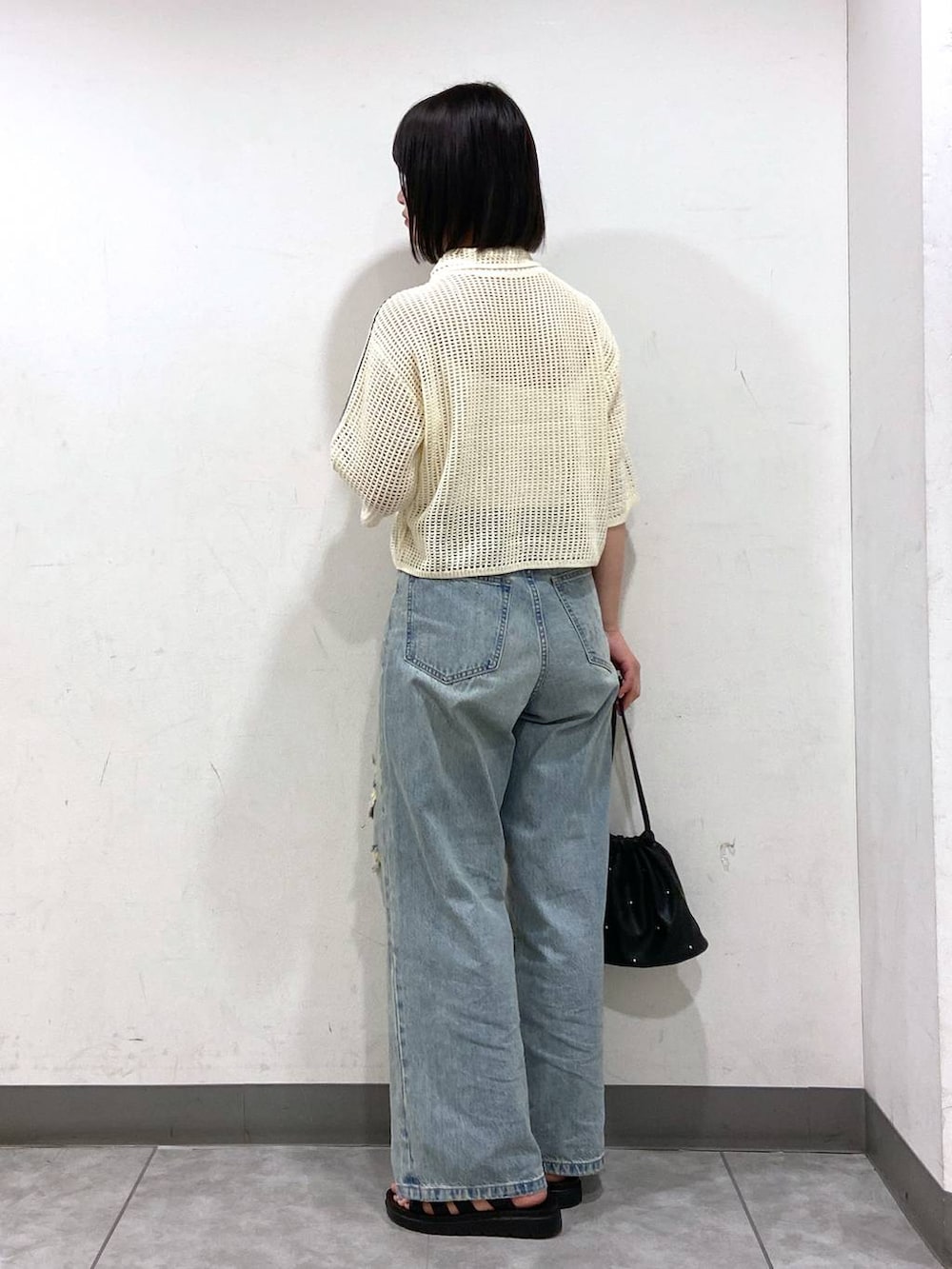 ブラック系のショルダーバッグ、ブラック系のスニーカー、ブルー系のデニムパンツを着用したレディースの夏コーディネートの3枚目の写真