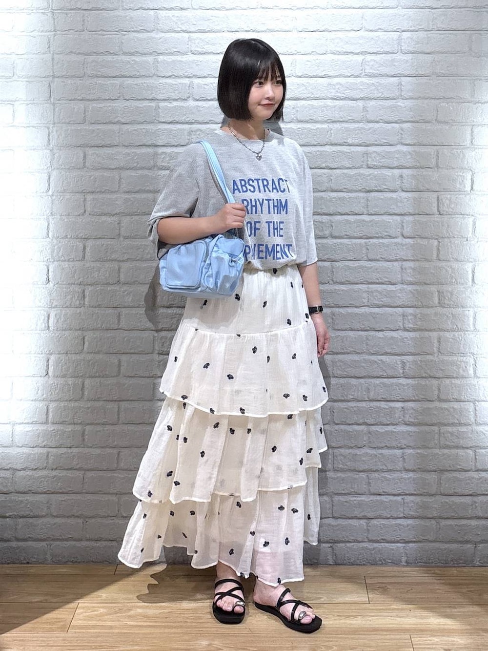グレー系のTシャツ/カットソー、ブラック系のサンダル、ホワイト系のスカートを着用したレディースの夏コーディネートの2枚目の写真