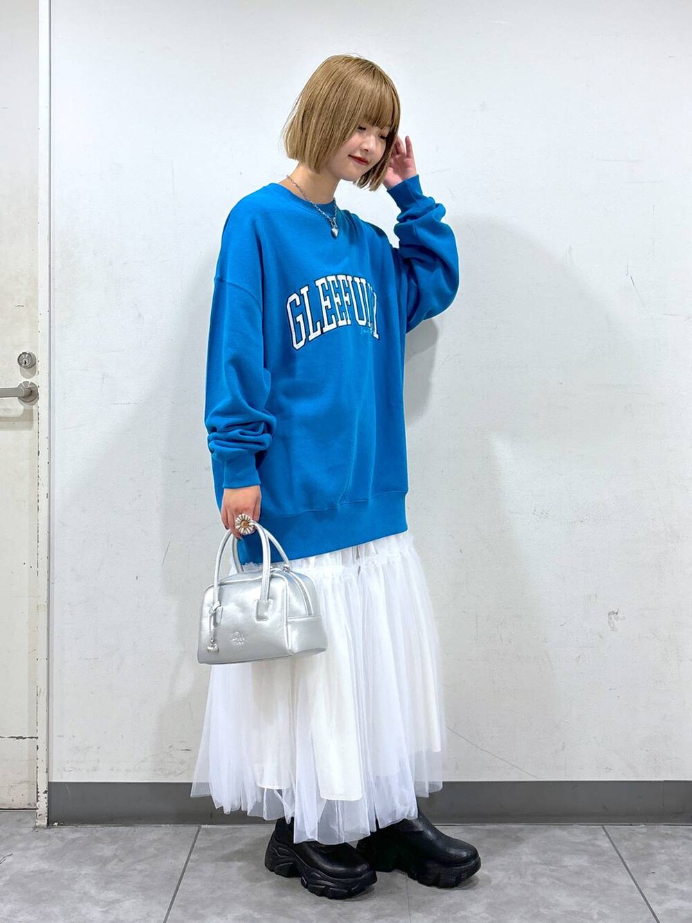 ベージュ系のスカート、ブルー系のスウェット、シルバー系のボストンバッグを着用したレディースの秋コーディネートの2枚目の写真