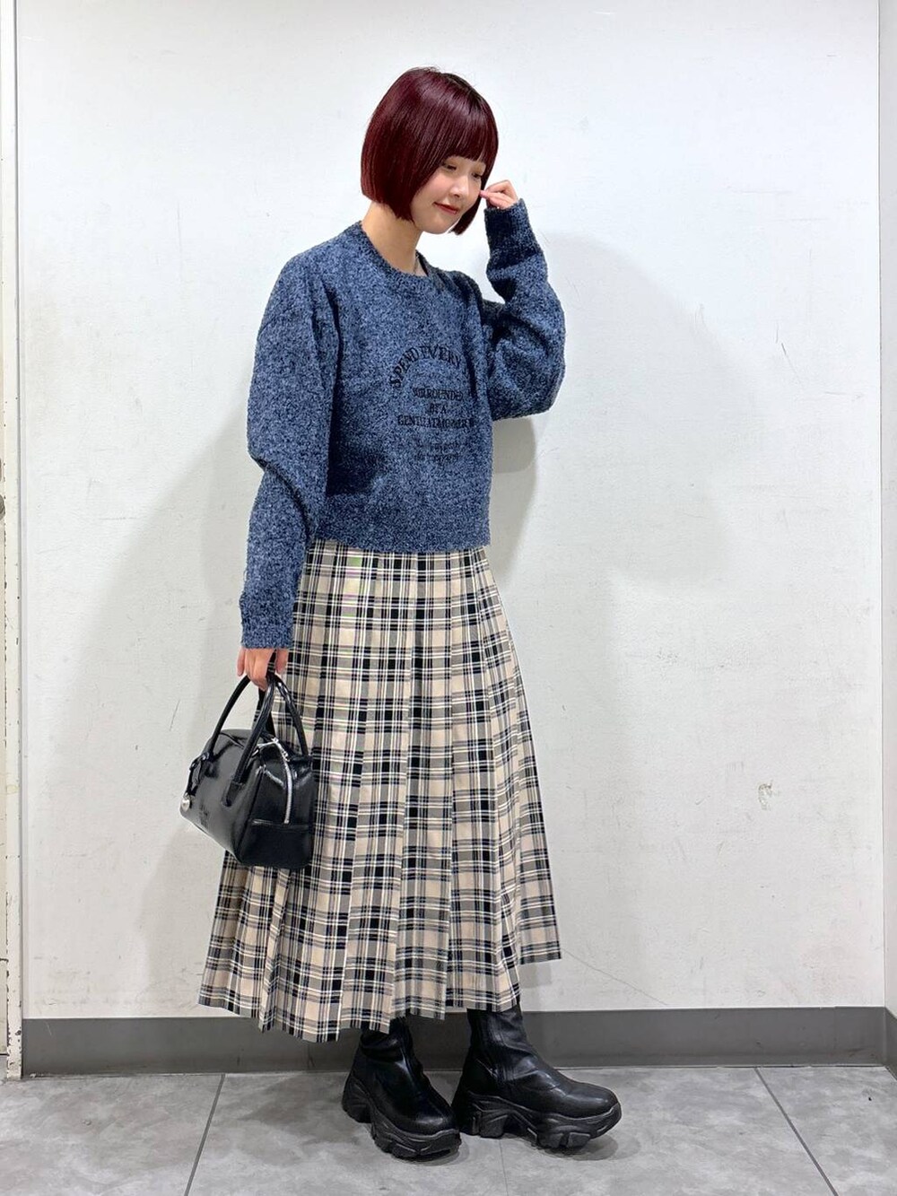 ブラック系のブーツ、ブラック系のボストンバッグ、ブルー系のニット/セーターを着用したレディースの秋コーディネートの2枚目の写真