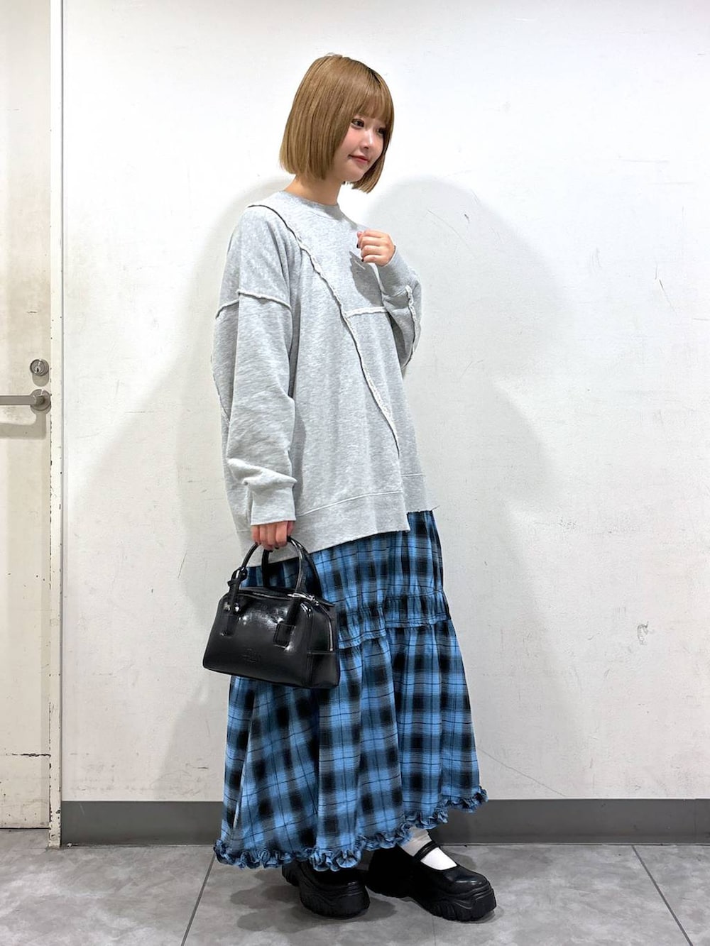 ブルー系のスカート、グレー系のスウェット、ブラック系のスニーカーを着用したレディースの秋コーディネートの2枚目の写真