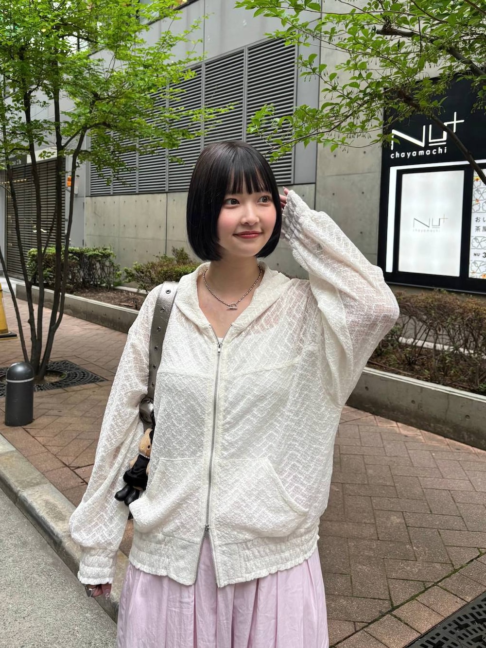 ホワイト系のパーカー、ピンク系のカーゴパンツ、シルバー系のスニーカーを着用したレディースの春コーディネートの3枚目の写真