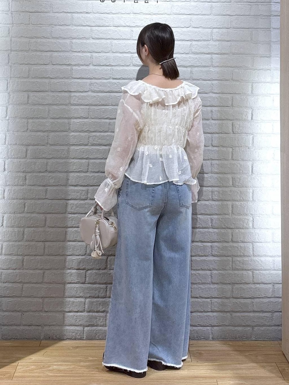 ホワイト系のボストンバッグ、ブルー系のデニムパンツ、ブラウン系のサンダルを着用したレディースの春コーディネートの3枚目の写真