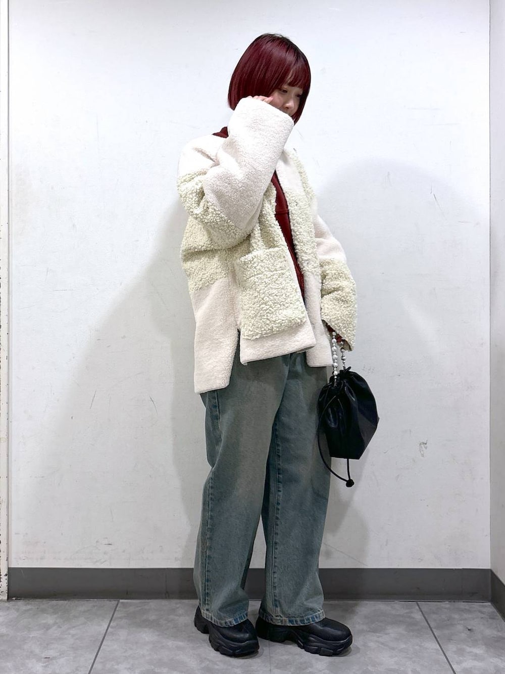 ブルー系のデニムパンツ、ブラック系のブーツ、ブラック系のショルダーバッグを着用したレディースの秋コーディネートの2枚目の写真