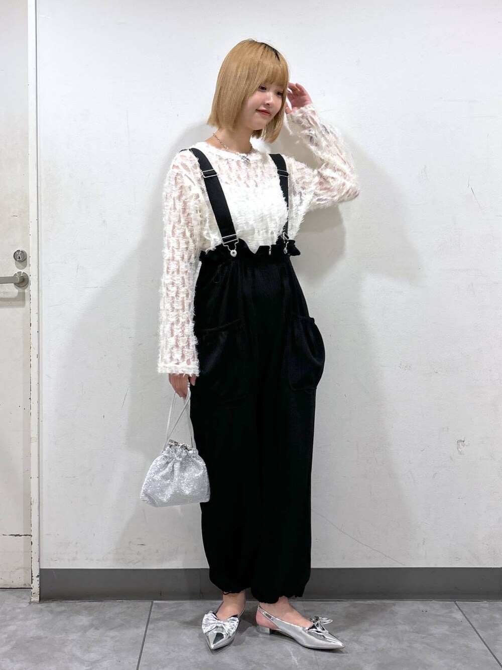 シルバー系のパンプス、ブラック系のワンピース、シルバー系のショルダーバッグを着用したレディースの秋コーディネートの2枚目の写真