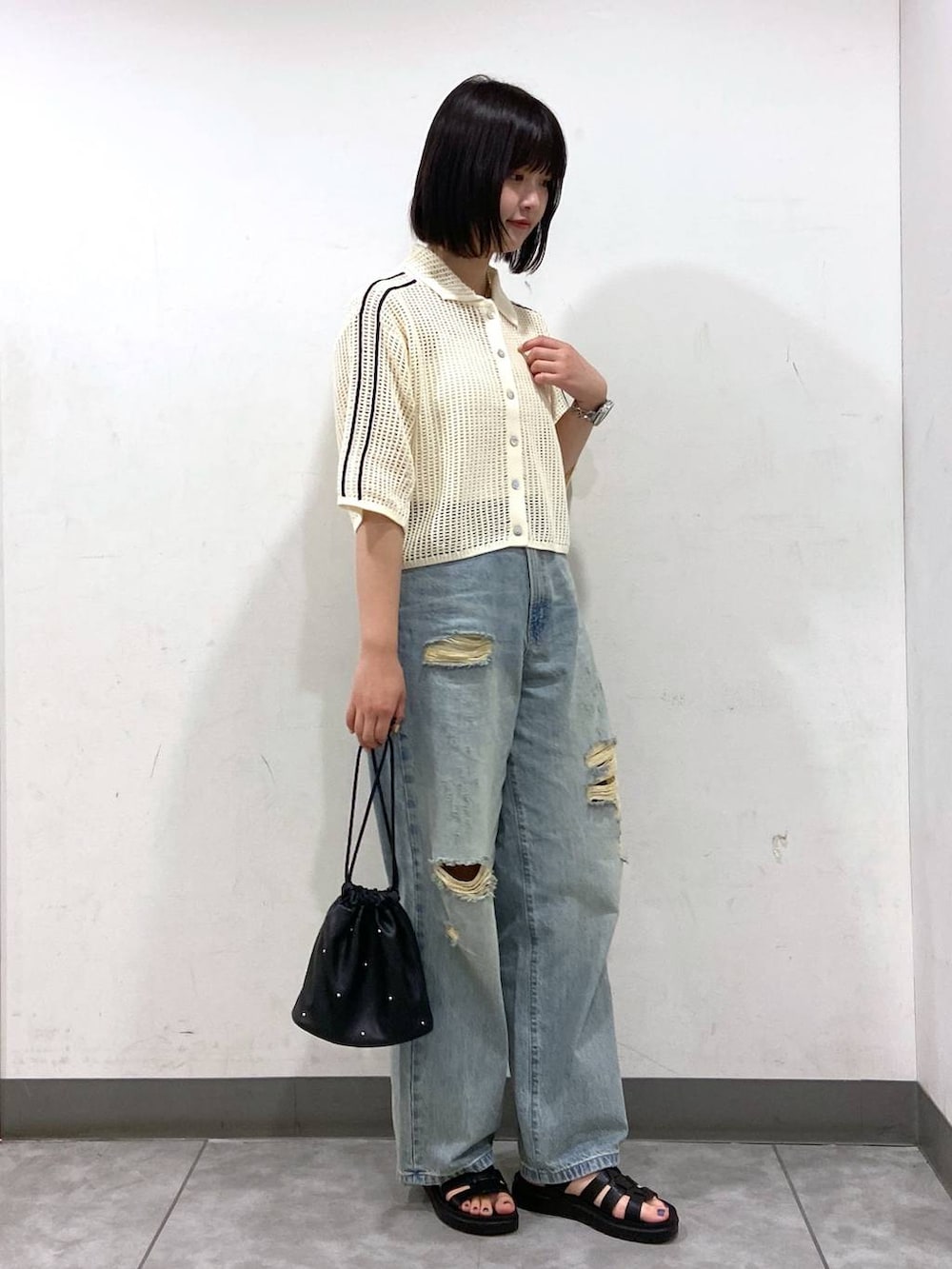 ブラック系のショルダーバッグ、ブラック系のスニーカー、ブルー系のデニムパンツを着用したレディースの夏コーディネートの2枚目の写真