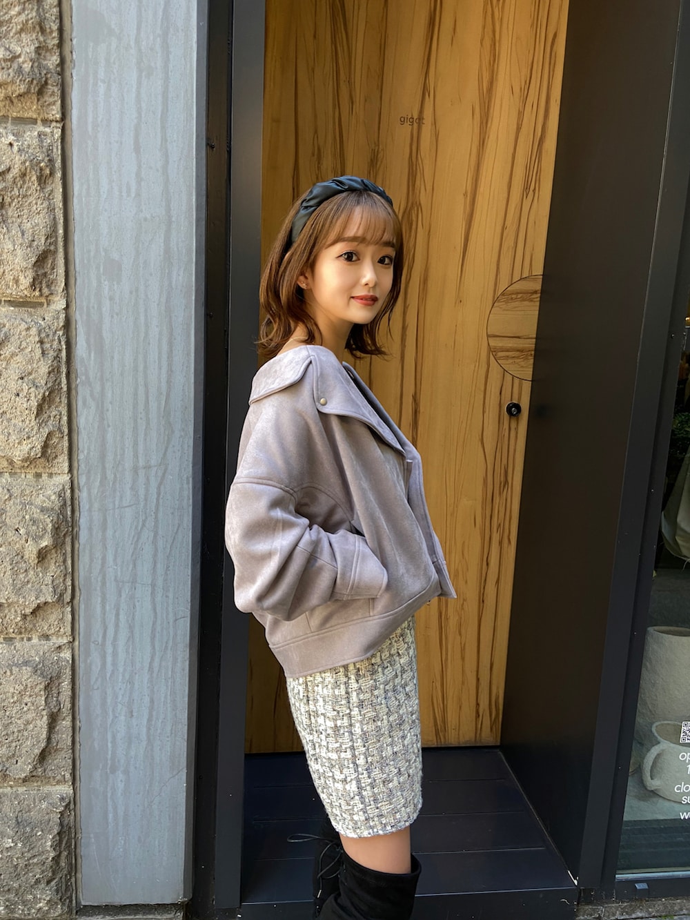 ベージュ系のブーツ、ブラウン系のライダースジャケット、ホワイト系のスカートを着用したレディースの冬コーディネートの3枚目の写真