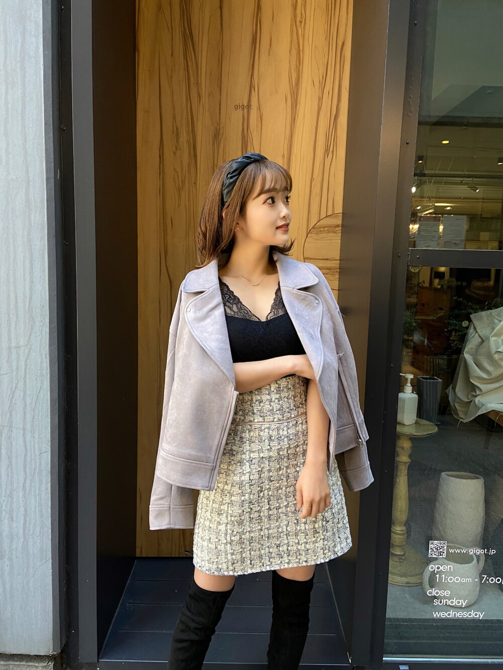 ベージュ系のブーツ、ブラウン系のライダースジャケット、ホワイト系のスカートを着用したレディースの冬コーディネートの2枚目の写真