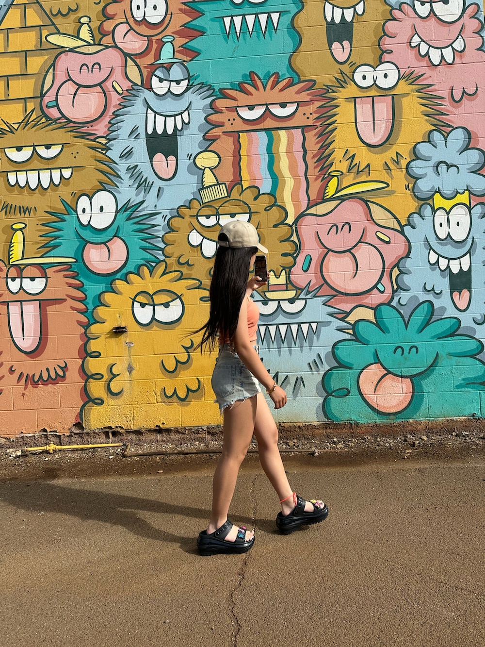 オレンジ系のキャミソール、ブルー系のパンツ、ブラック系のサンダルを着用したレディースの春コーディネートの2枚目の写真