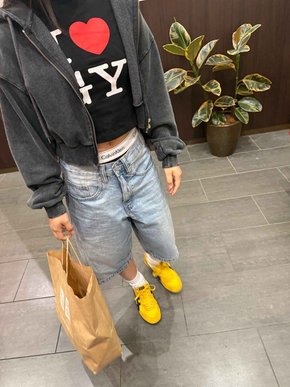 イエロー系のスニーカー、ブルー系のパンツ、ブラック系のTシャツ/カットソーを着用したレディースの春コーディネートの2枚目の写真