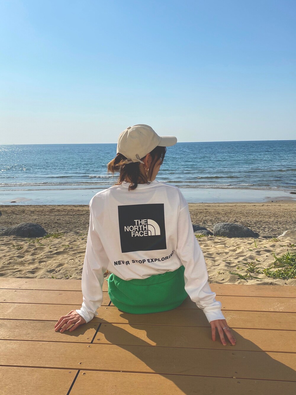 グリーン系のスカート、ホワイト系のスニーカー、ホワイト系のTシャツ/カットソーを着用したレディースの春コーディネートの3枚目の写真