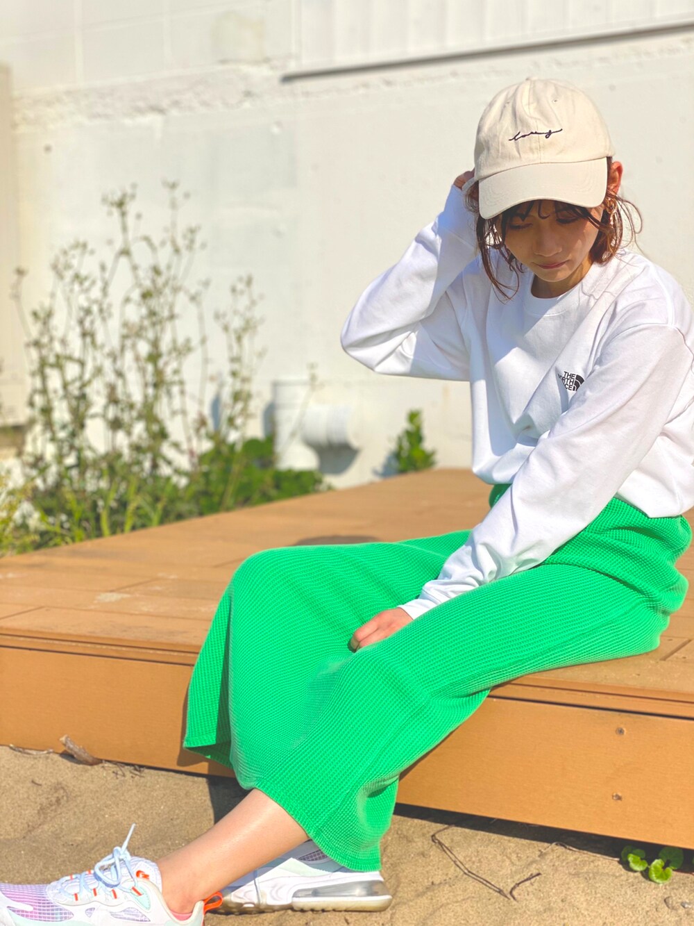 グリーン系のスカート、ホワイト系のスニーカー、ホワイト系のTシャツ/カットソーを着用したレディースの春コーディネートの2枚目の写真