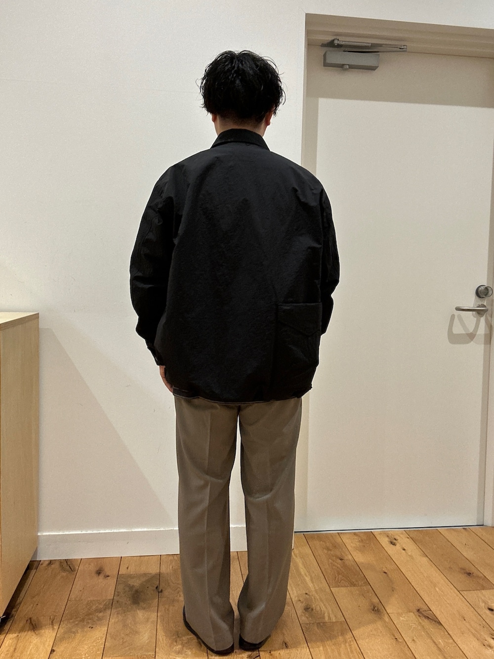 グレー系のTシャツ/カットソー、ブラック系のナイロンジャケット、ベージュ系のその他パンツを着用したメンズの冬コーディネートの3枚目の写真