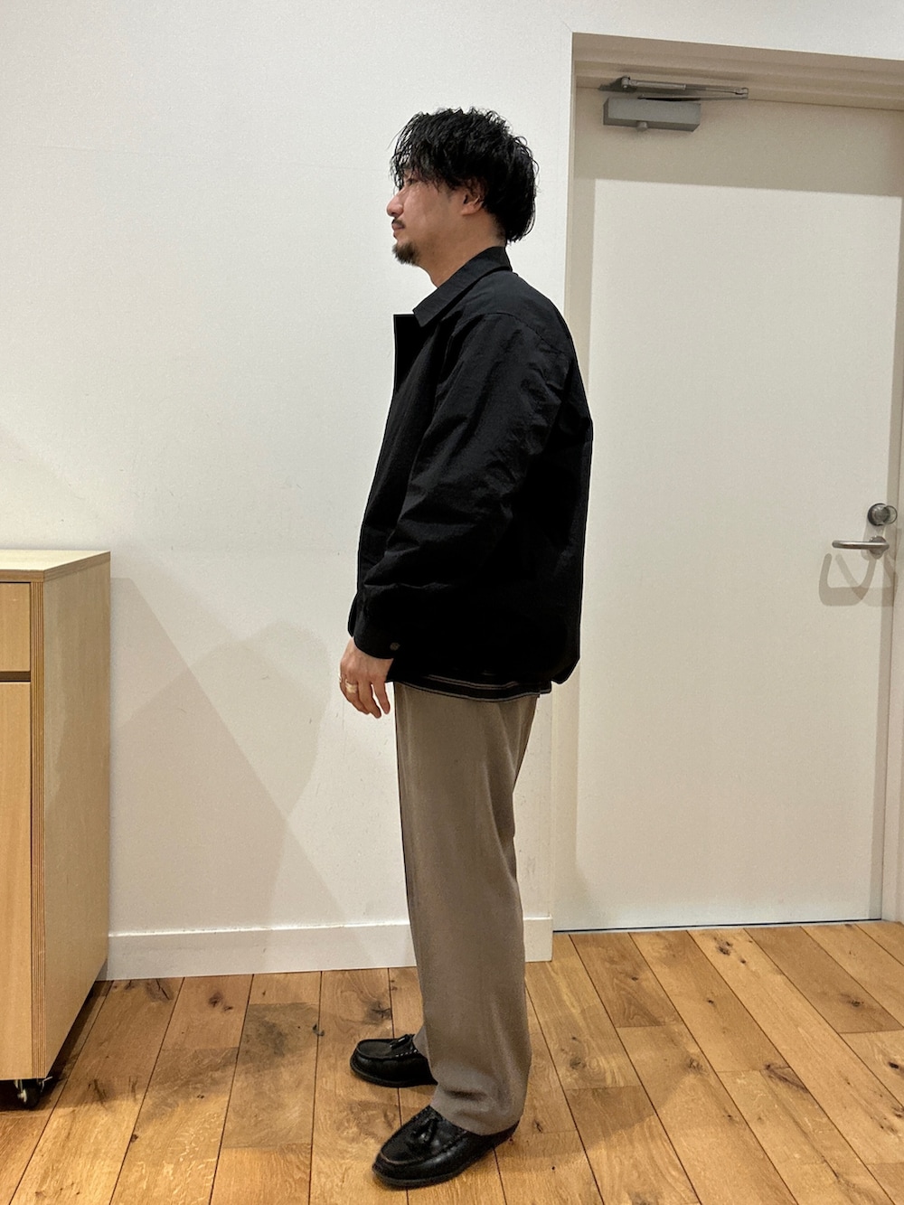 グレー系のTシャツ/カットソー、ブラック系のナイロンジャケット、ベージュ系のその他パンツを着用したメンズの冬コーディネートの2枚目の写真