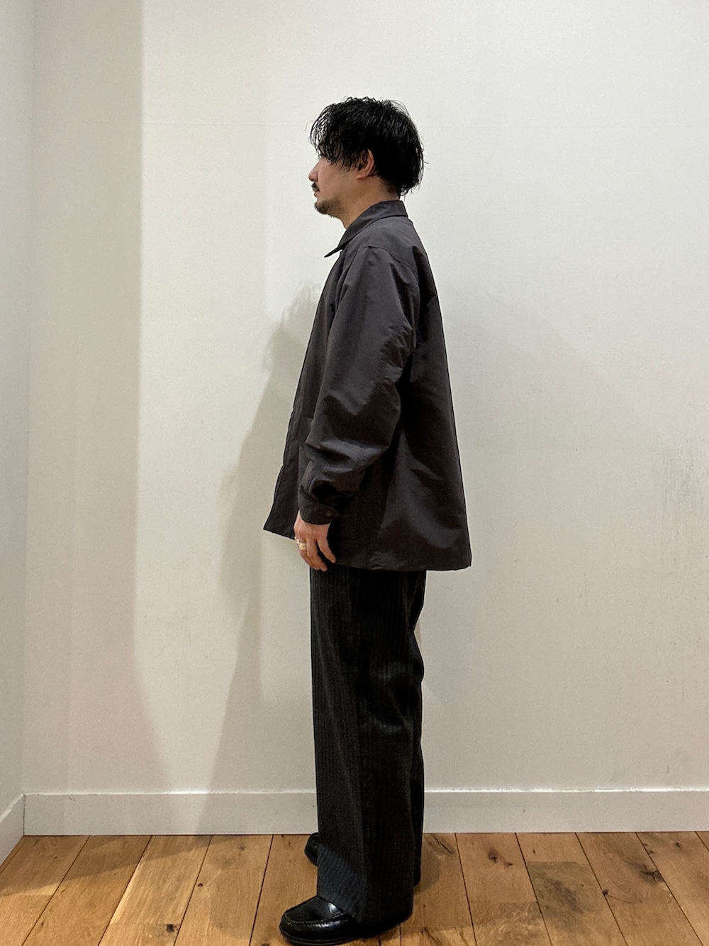 グレー系のスラックス、グレー系のTシャツ/カットソー、グレー系のナイロンジャケットを着用したメンズの春コーディネートの2枚目の写真