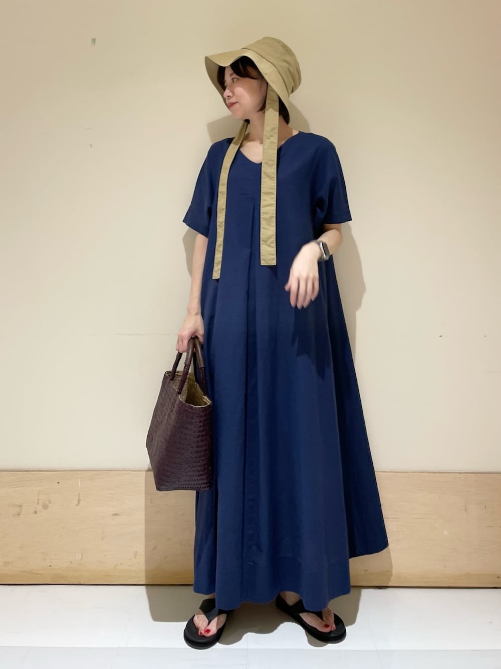 ブルー系のワンピース、ブラウン系のハンドバッグ、ブラック系のサンダルを着用したレディースの夏コーディネートの3枚目の写真
