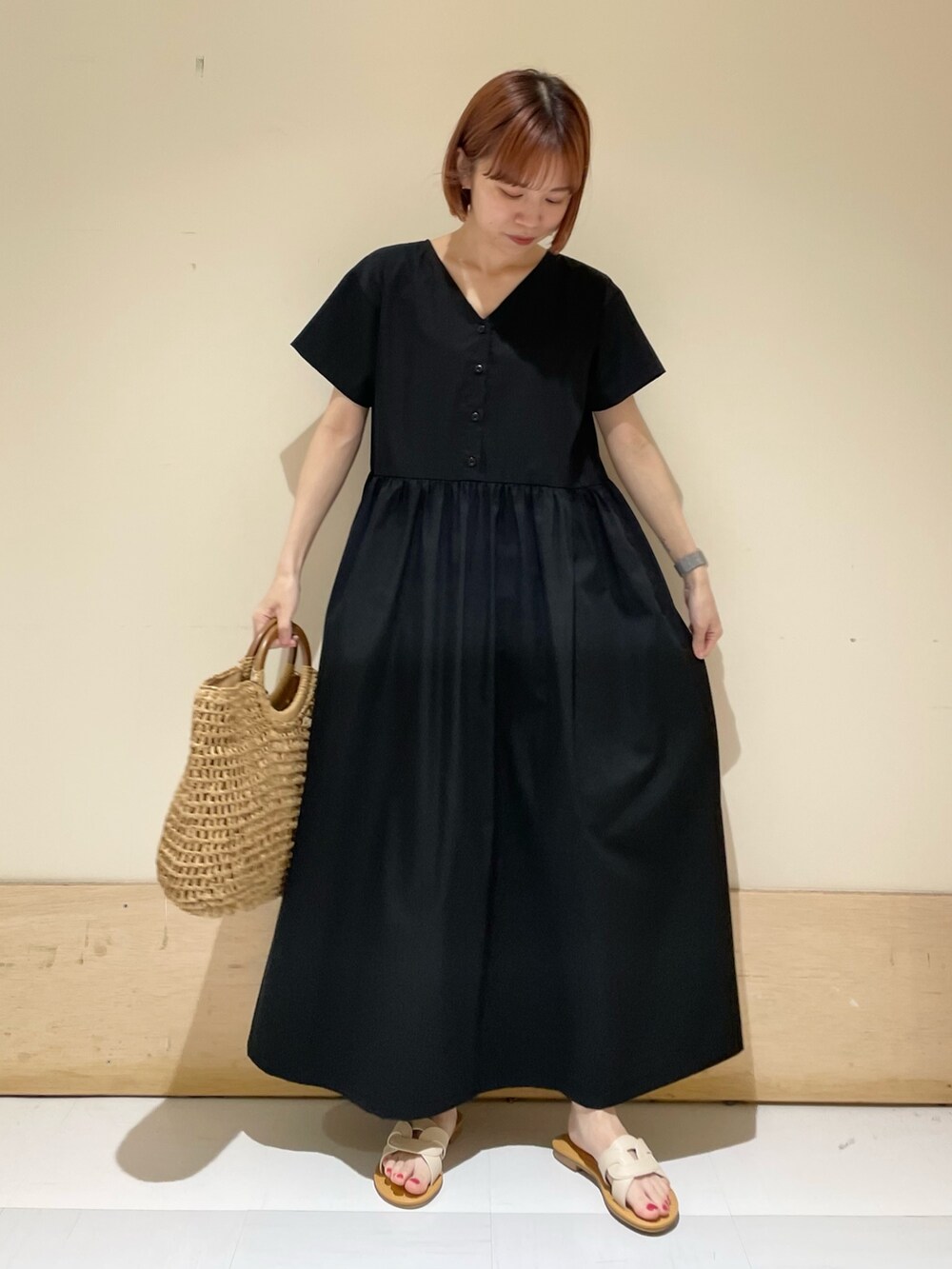 ホワイト系のサンダル、ベージュ系のかごバッグ、ブラック系のワンピースを着用したレディースの春コーディネートの2枚目の写真