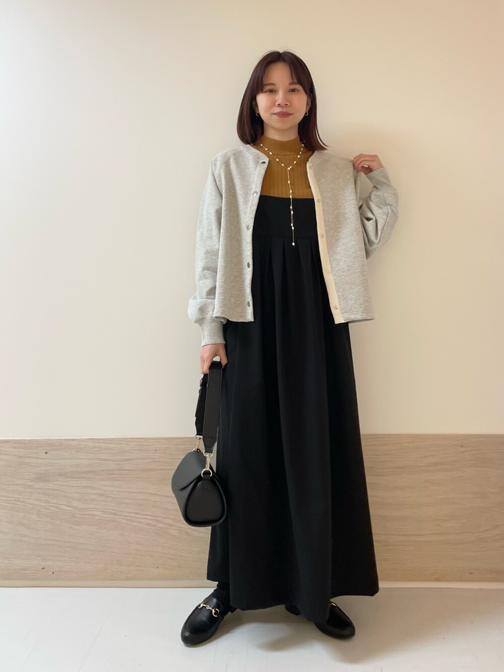 グレー系のカーディガン/ボレロ、イエロー系のニット/セーター、ブラック系のワンピースを着用したレディースの春コーディネートの2枚目の写真