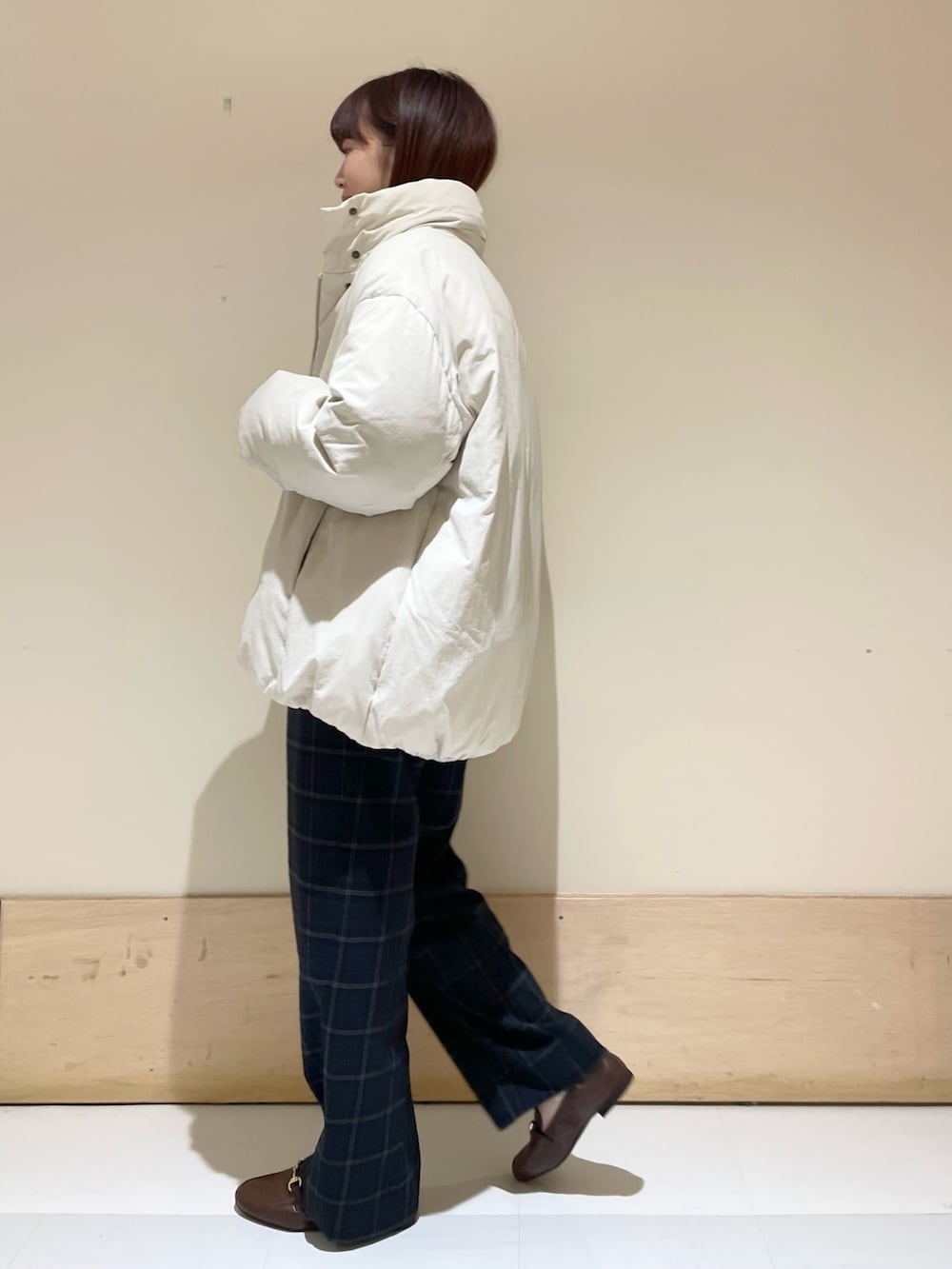 グリーン系のニット/セーター、ホワイト系のダウンジャケット/コート、ブラウン系のローファーを着用したレディースの秋コーディネートの5枚目の写真