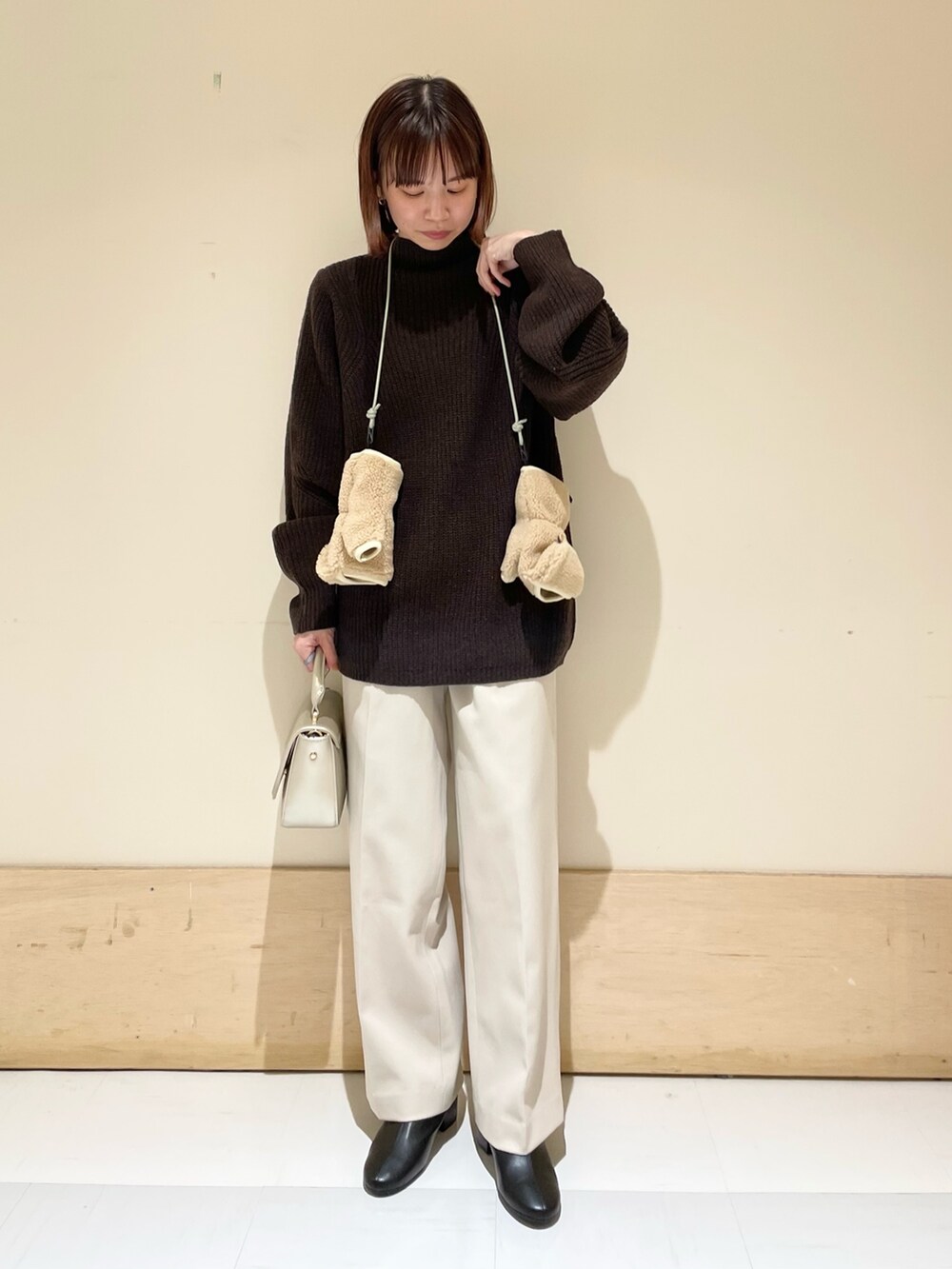 ブラウン系のニット/セーター、ゴールド系のショルダーバッグ、ホワイト系のその他パンツを着用したレディースの冬コーディネートの4枚目の写真