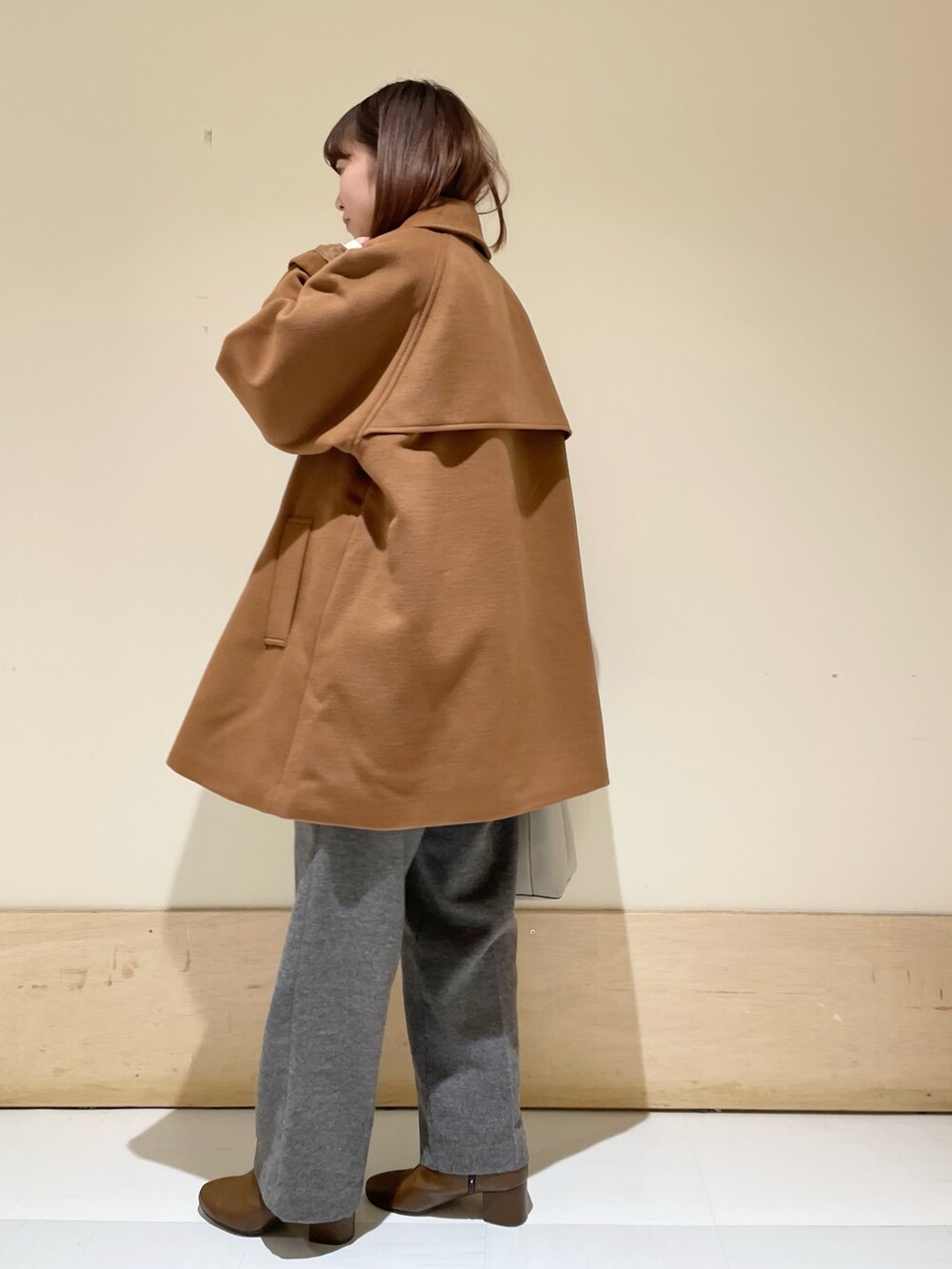 イエロー系のピーコート、ホワイト系のニット/セーター、グレー系のその他パンツを着用したレディースの冬コーディネートの8枚目の写真
