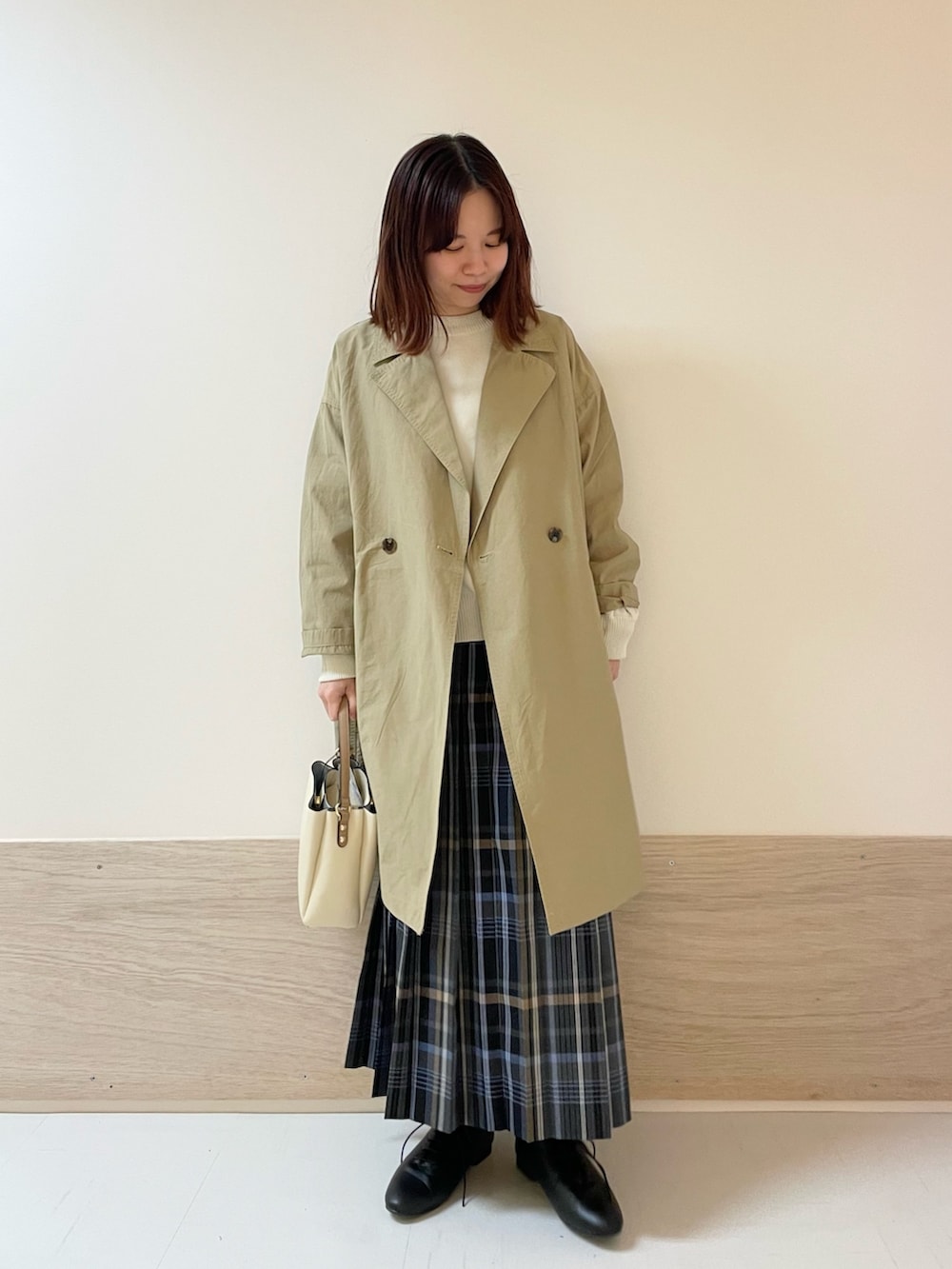 グレー系のスカート、ホワイト系のニット/セーター、ベージュ系のその他アウターを着用したレディースの春コーディネートの3枚目の写真