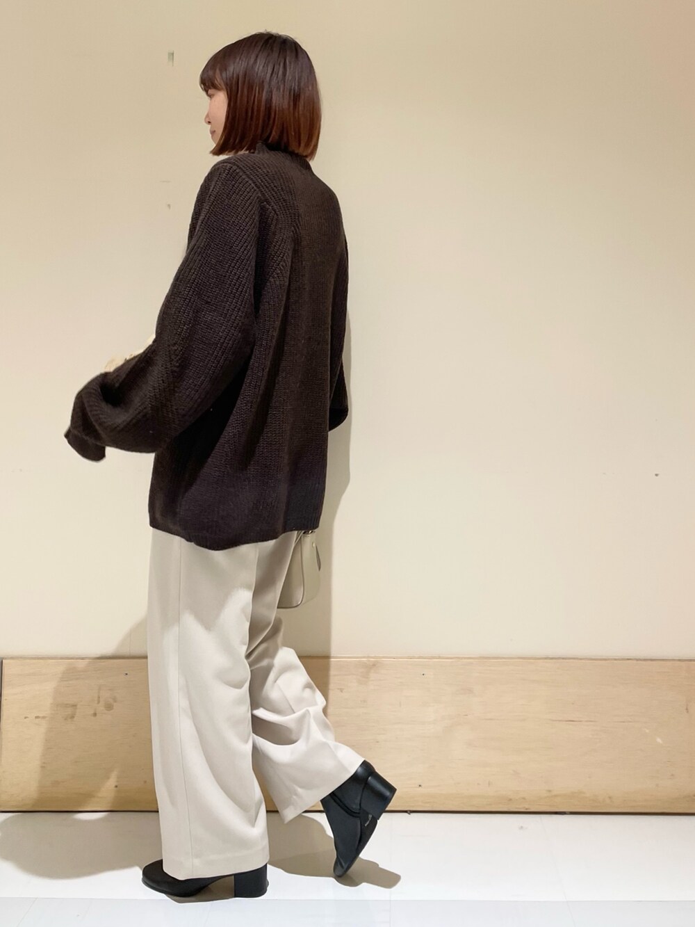 ブラウン系のニット/セーター、ゴールド系のショルダーバッグ、ホワイト系のその他パンツを着用したレディースの冬コーディネートの6枚目の写真