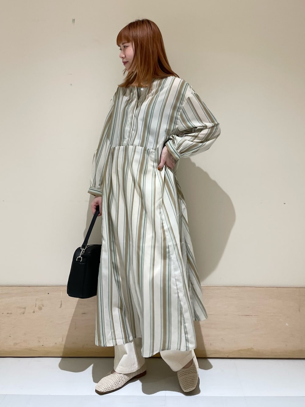 グリーン系のワンピース、ホワイト系のパンプス、ブラック系のショルダーバッグを着用したレディースの春コーディネートの3枚目の写真