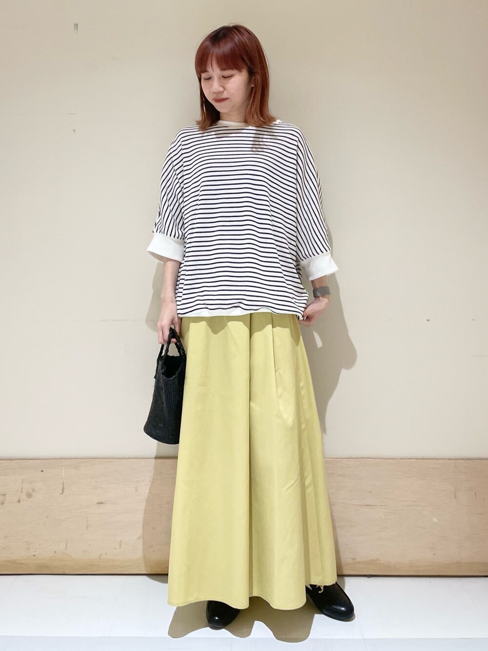 ホワイト系のTシャツ/カットソー、イエロー系のスカート、ブラック系のローファーを着用したレディースの春コーディネートの2枚目の写真