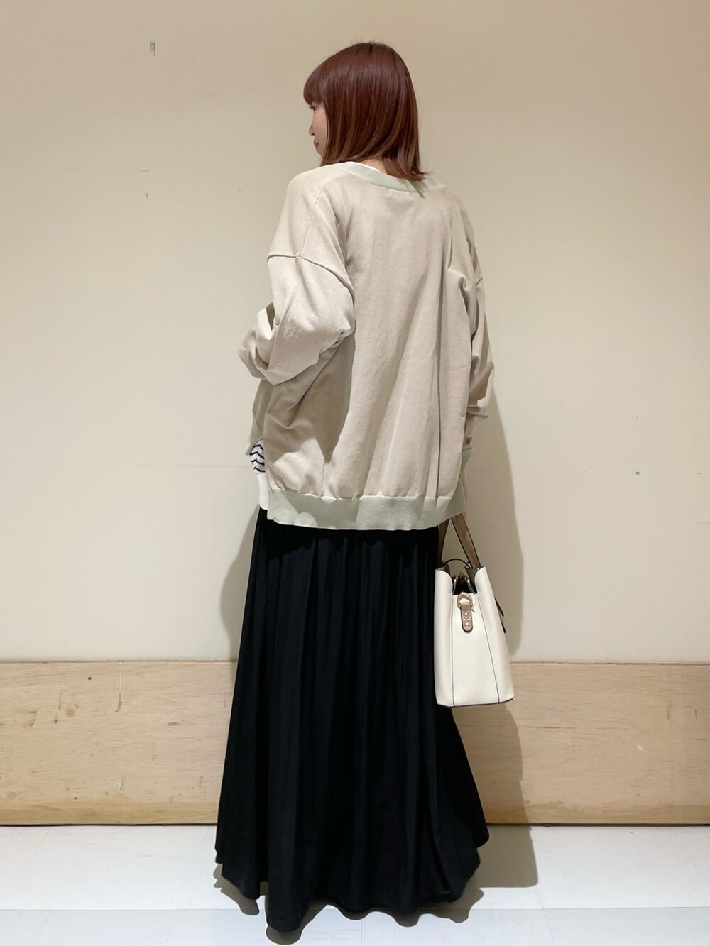 ブラック系のスカート、ホワイト系のTシャツ/カットソー、ベージュ系のカーディガン/ボレロを着用したレディースの春コーディネートの7枚目の写真