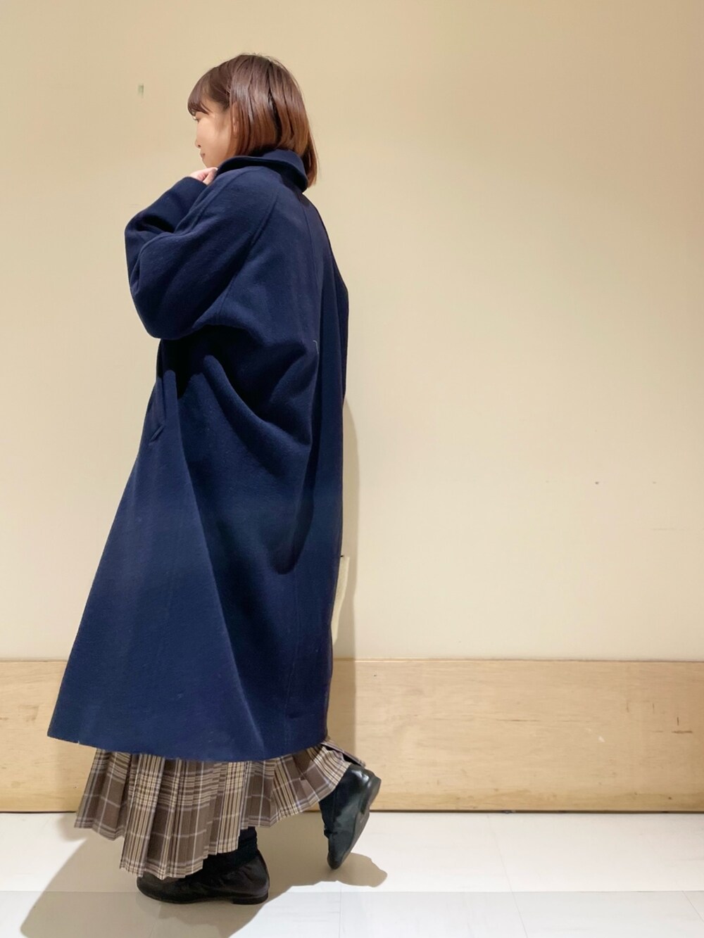 ブラック系のニット/セーター、ホワイト系のショルダーバッグ、ブラウン系のスカートを着用したレディースの冬コーディネートの6枚目の写真