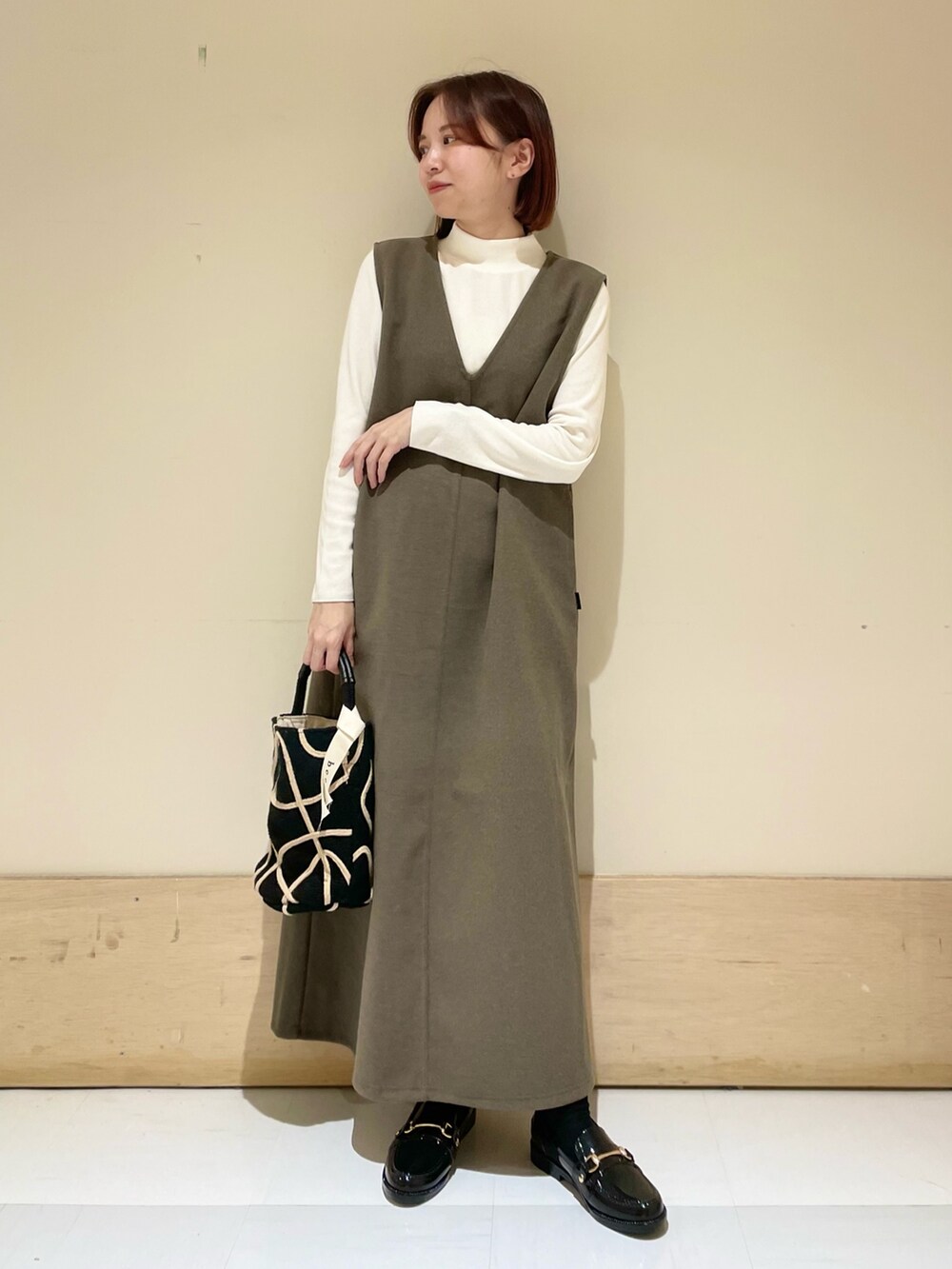 ブラウン系のワンピース、ホワイト系のTシャツ/カットソー、ブラック系のショルダーバッグを着用したレディースの秋コーディネートの3枚目の写真