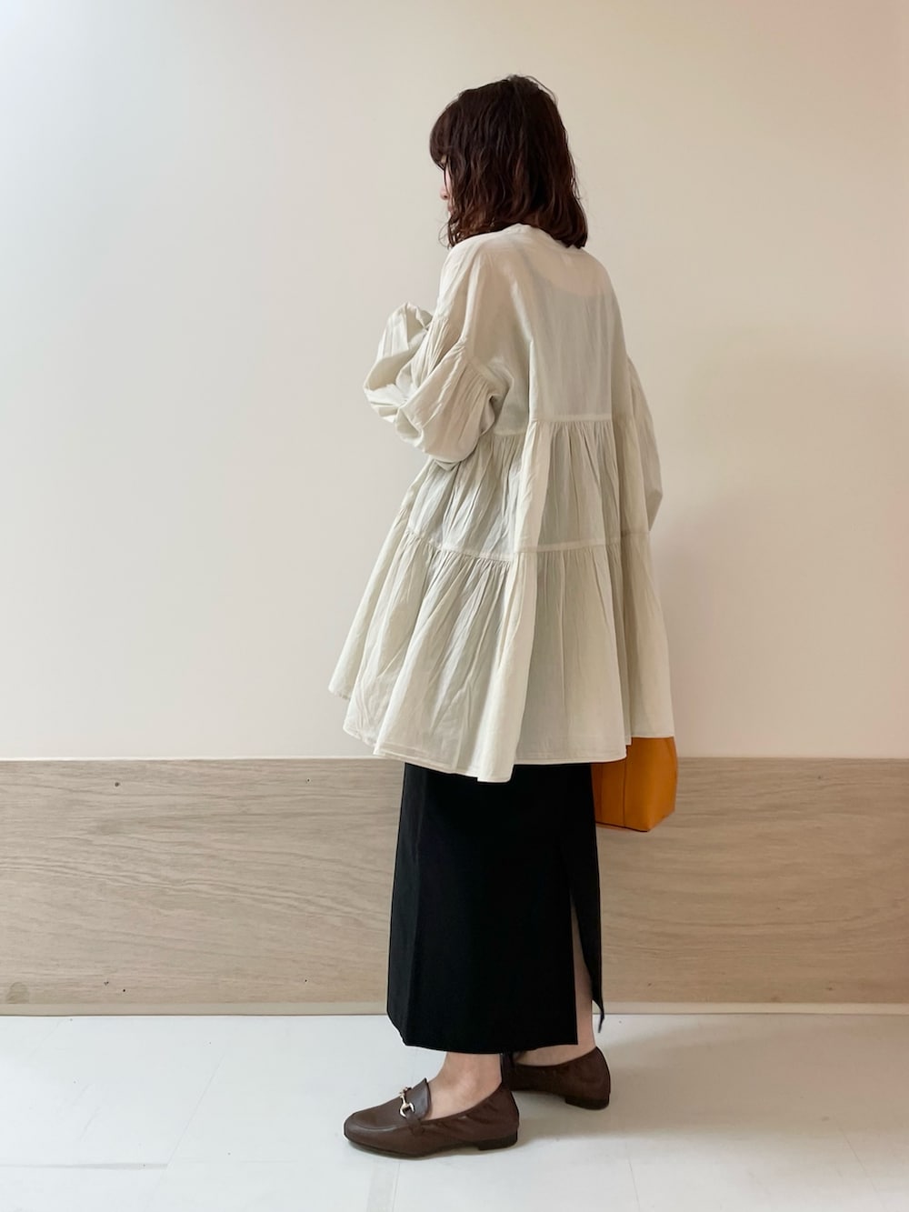 ブラック系のスカート、ホワイト系のチュニックを着用したレディースの春コーディネートの5枚目の写真