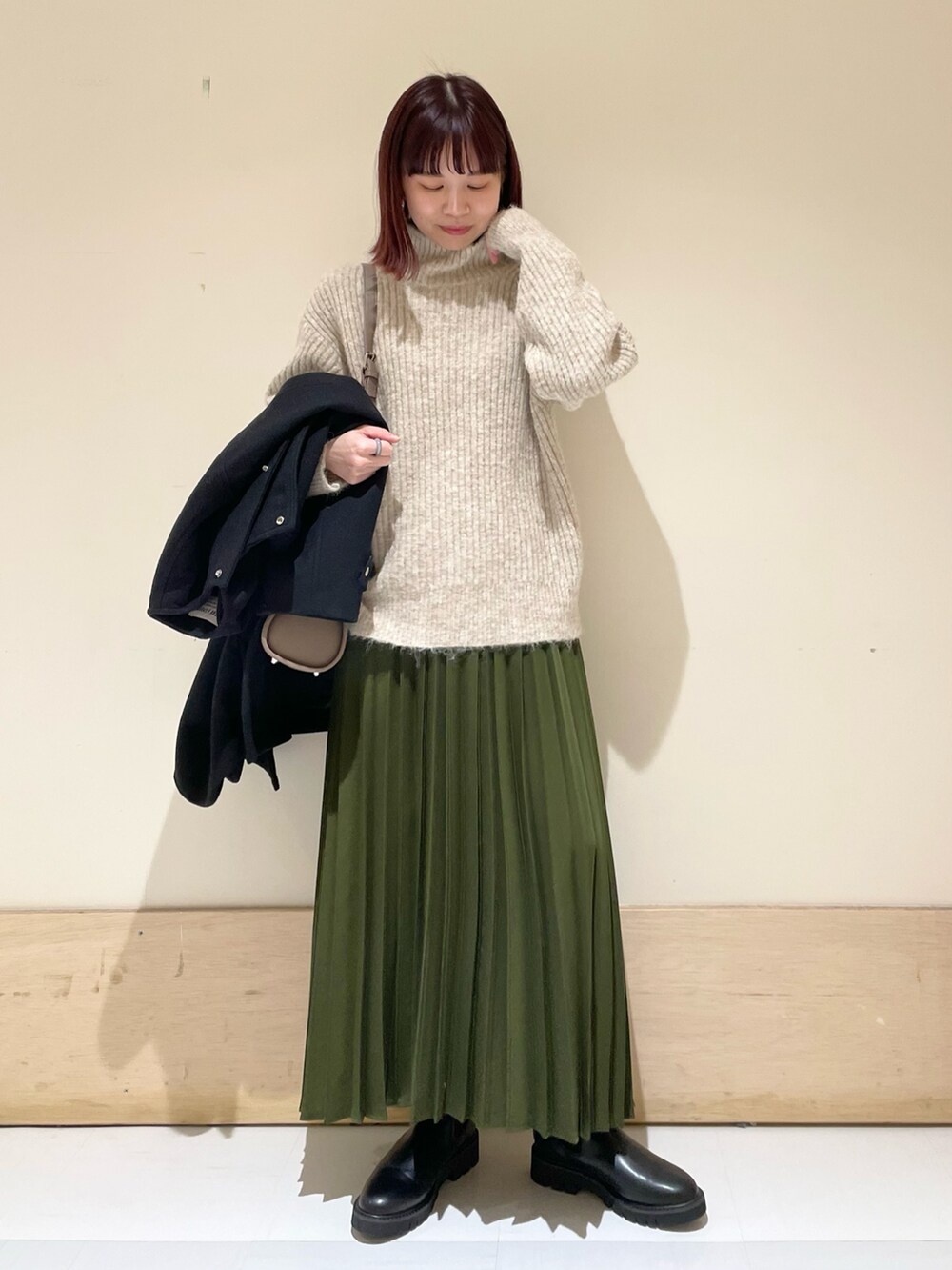 ブラック系のその他アウター、ブラック系のブーツ、グリーン系のスカートを着用したレディースの冬コーディネートの7枚目の写真