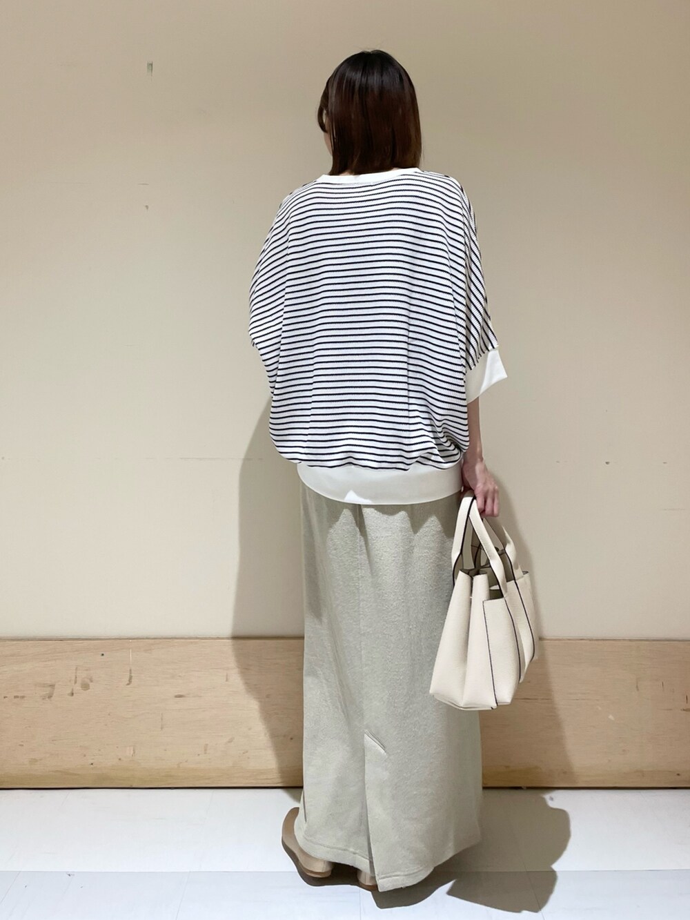 ベージュ系のスカート、ホワイト系のTシャツ/カットソー、ホワイト系のトートバッグを着用したレディースの秋コーディネートの7枚目の写真