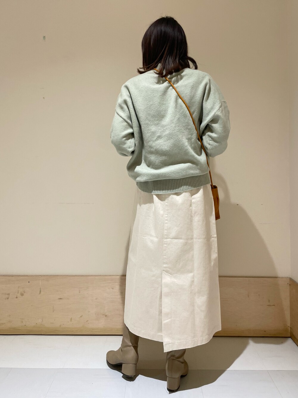 グリーン系のニット/セーター、イエロー系のショルダーバッグ、ホワイト系のスカートを着用したレディースの冬コーディネートの3枚目の写真