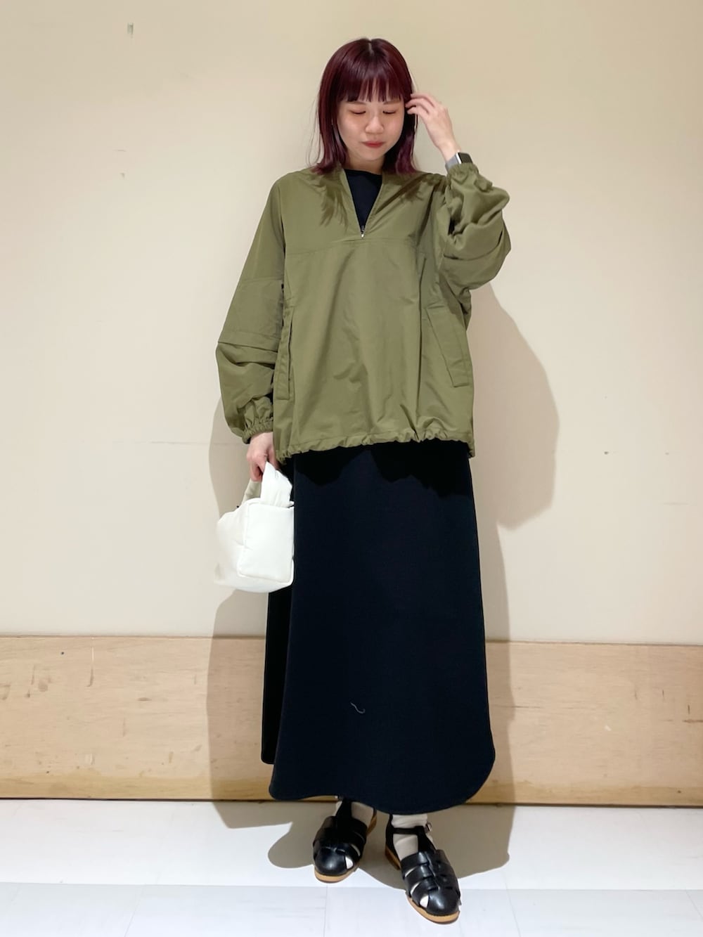 ホワイト系のハンドバッグ、ブラック系のワンピース、グリーン系のその他トップスを着用したレディースの春コーディネートの3枚目の写真