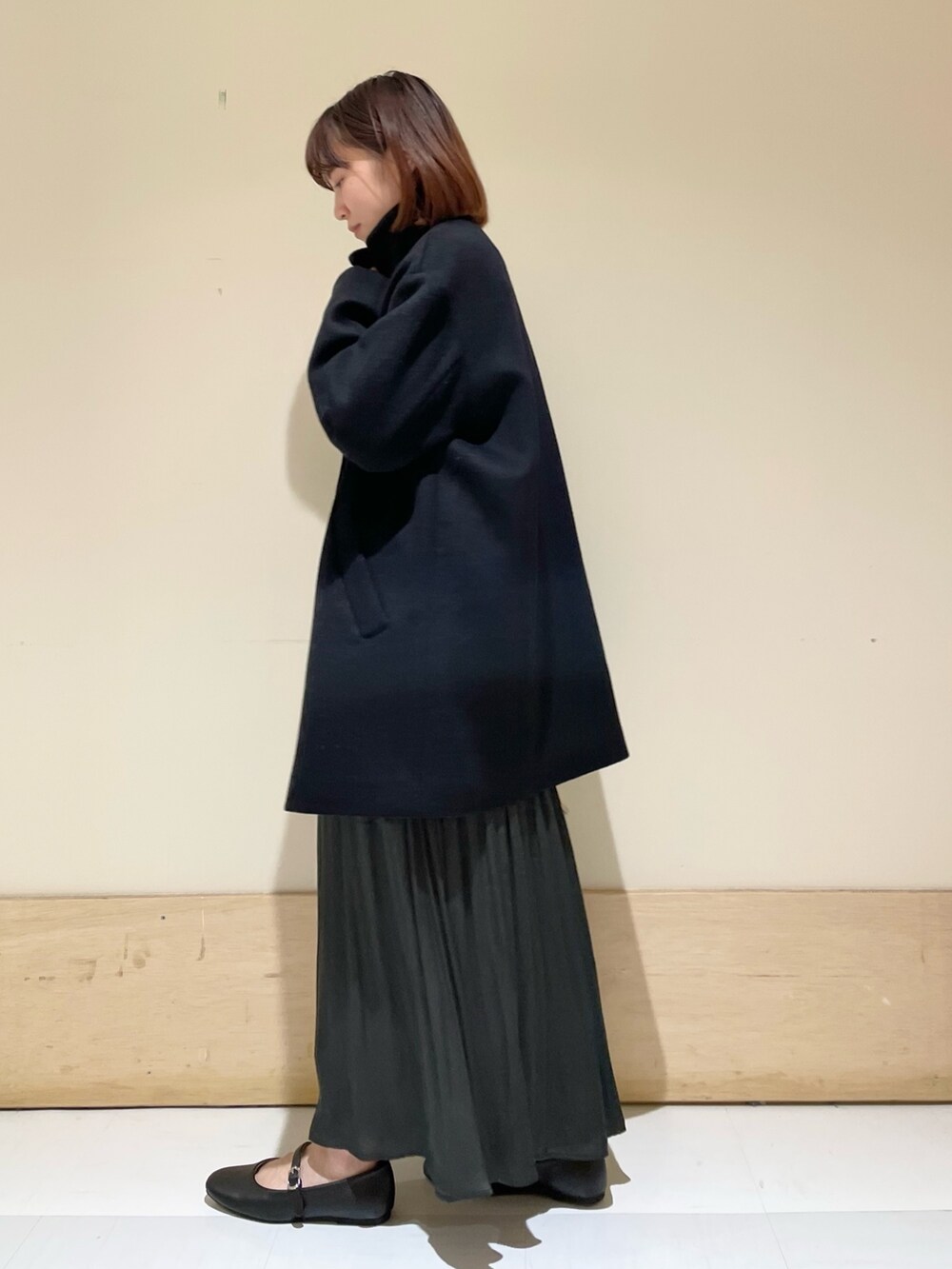 グリーン系のスカート、グレー系のニット/セーター、ブラック系のその他アウターを着用したレディースの冬コーディネートの6枚目の写真